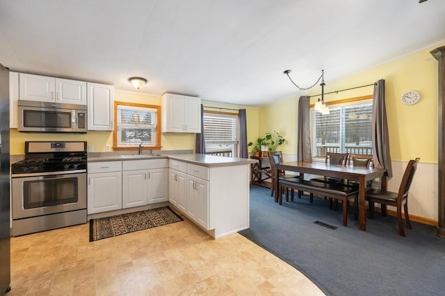 kitchen featuring white cabinets, decorative light fixtures, and stainless steel appliances