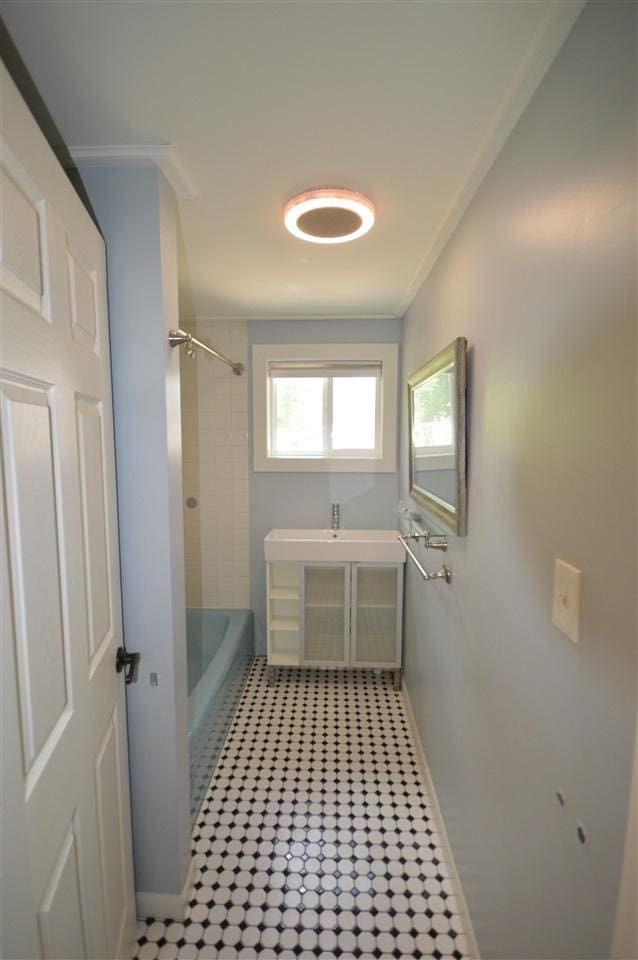 bathroom with tiled shower / bath, crown molding, and sink