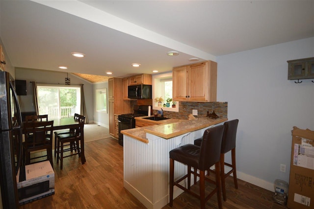 kitchen with a kitchen bar, kitchen peninsula, a healthy amount of sunlight, and black appliances