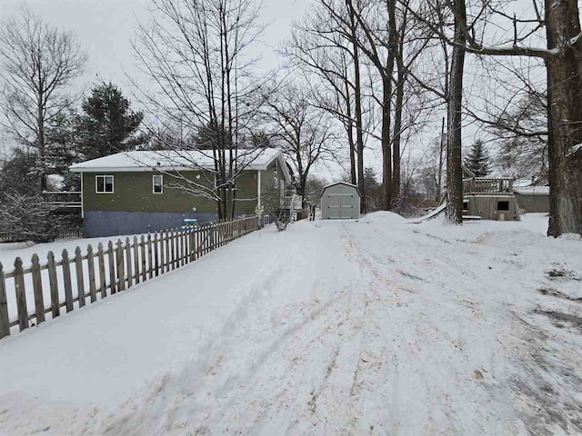 snowy yard featuring a storage unit