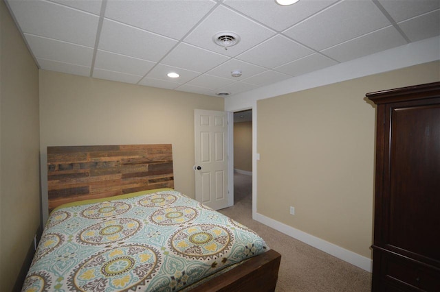 carpeted bedroom featuring a drop ceiling