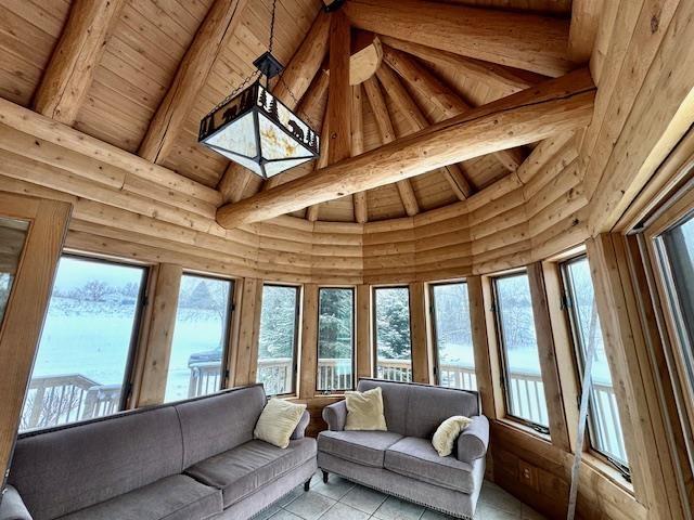 sunroom with a healthy amount of sunlight, vaulted ceiling with beams, and wooden ceiling