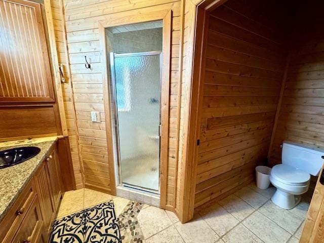 bathroom featuring a shower with door, tile patterned flooring, toilet, vanity, and wood walls