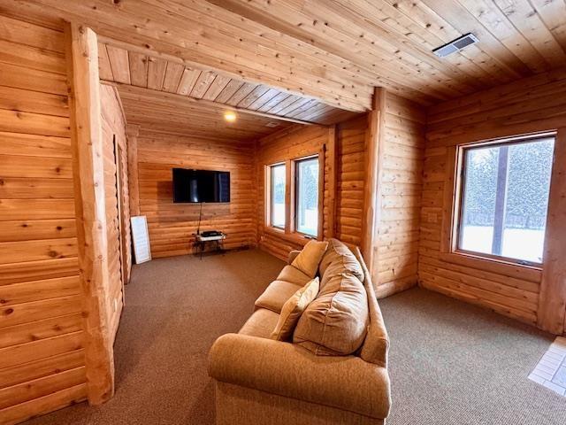 carpeted living room featuring wooden ceiling and log walls