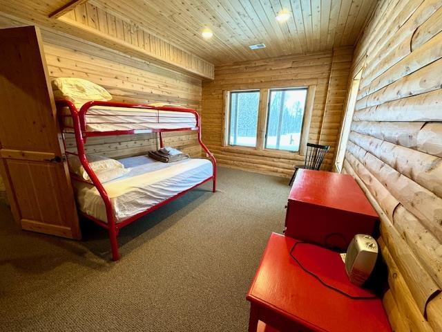 carpeted bedroom featuring wooden ceiling and rustic walls