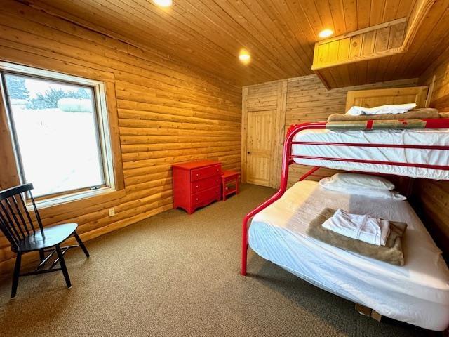 carpeted bedroom featuring rustic walls