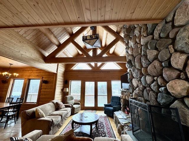 living room featuring plenty of natural light, vaulted ceiling with beams, wood ceiling, and a fireplace