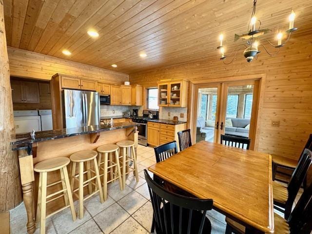 dining space with french doors, wood walls, independent washer and dryer, and a healthy amount of sunlight