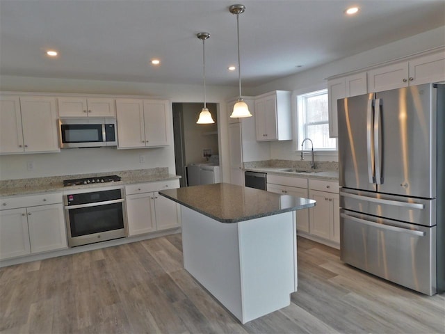 kitchen with white cabinets, sink, hanging light fixtures, separate washer and dryer, and stainless steel appliances