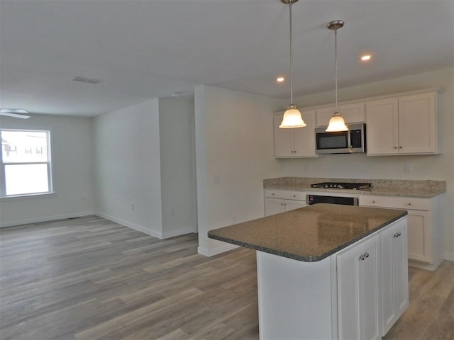 kitchen featuring appliances with stainless steel finishes, light wood-type flooring, a kitchen island, pendant lighting, and white cabinetry