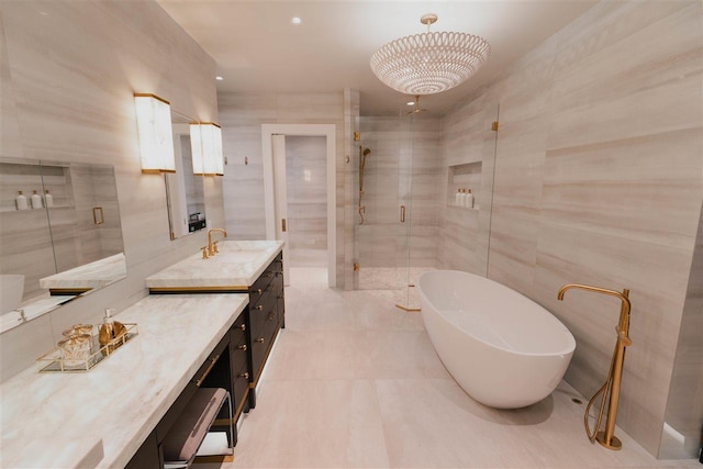 bathroom with a notable chandelier, shower with separate bathtub, vanity, and tile walls