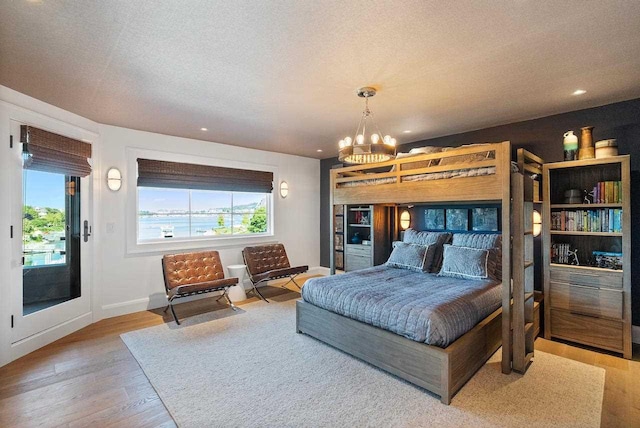 bedroom featuring a textured ceiling, hardwood / wood-style flooring, and a notable chandelier