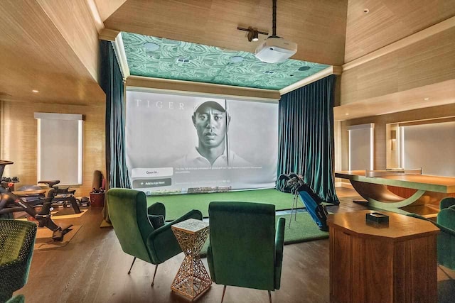 game room featuring wood walls, wood-type flooring, and a high ceiling