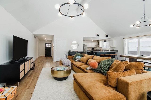 living room featuring high vaulted ceiling, a chandelier, and light wood-type flooring