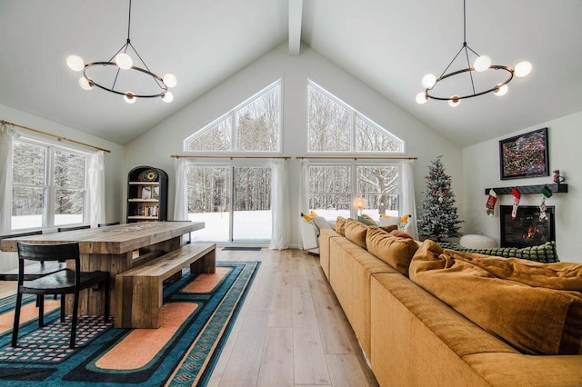 living room featuring beam ceiling, light hardwood / wood-style floors, high vaulted ceiling, and a notable chandelier