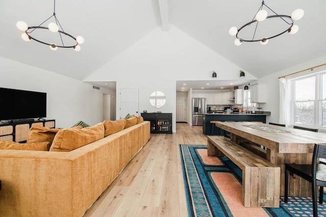 interior space featuring beam ceiling, light wood-type flooring, high vaulted ceiling, and a notable chandelier