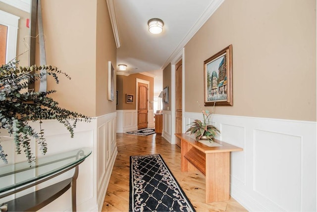 corridor with ornamental molding and light hardwood / wood-style floors