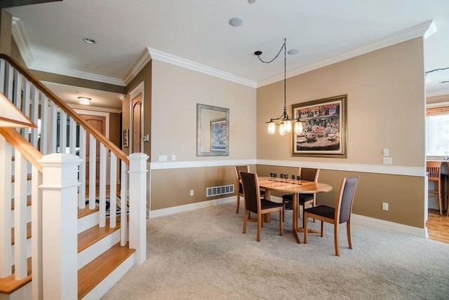 carpeted dining space featuring crown molding and a chandelier