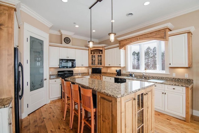 kitchen with light stone counters, ornamental molding, pendant lighting, a kitchen island, and black appliances