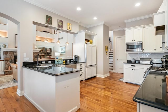 kitchen with kitchen peninsula, white cabinetry, pendant lighting, and stainless steel microwave