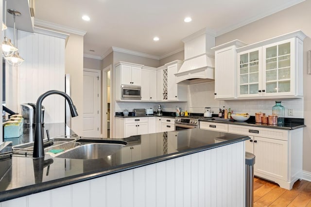 kitchen featuring sink, light hardwood / wood-style floors, pendant lighting, crown molding, and appliances with stainless steel finishes