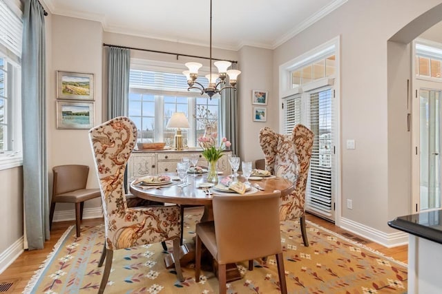 dining area featuring light hardwood / wood-style floors, a notable chandelier, and crown molding