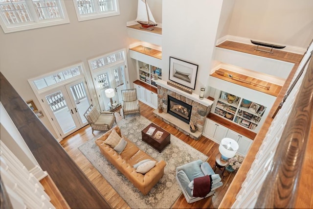 living room featuring light hardwood / wood-style flooring, a healthy amount of sunlight, a high ceiling, french doors, and a fireplace