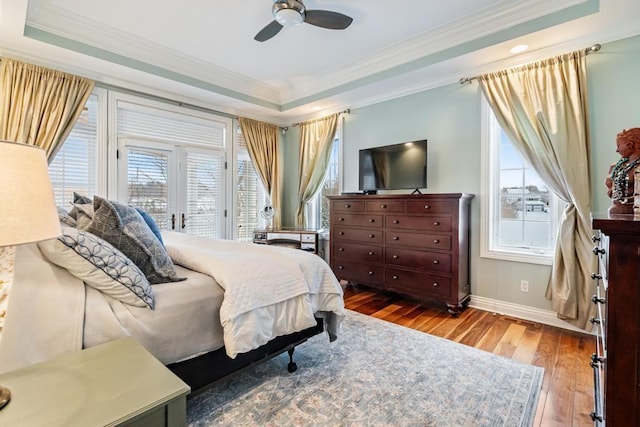 bedroom with hardwood / wood-style floors, a tray ceiling, crown molding, ceiling fan, and access to exterior