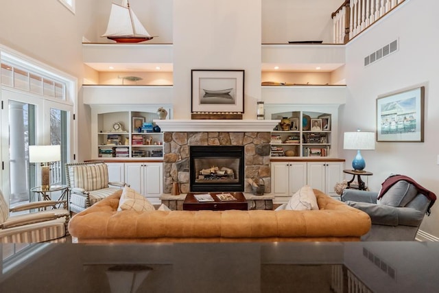 living room with a high ceiling, plenty of natural light, and a stone fireplace