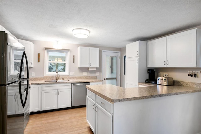 kitchen with black fridge, white cabinets, dishwasher, and sink