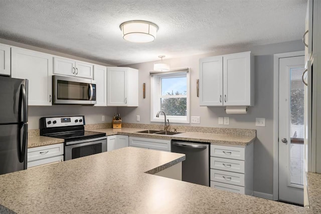 kitchen with stainless steel appliances, white cabinetry, sink, and a textured ceiling