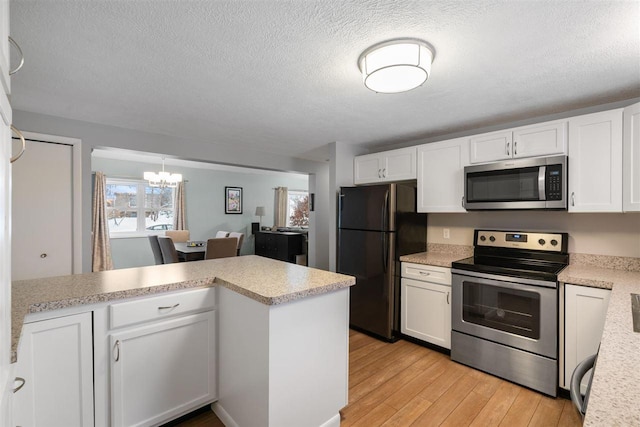 kitchen featuring kitchen peninsula, a chandelier, stainless steel appliances, light wood-type flooring, and white cabinets