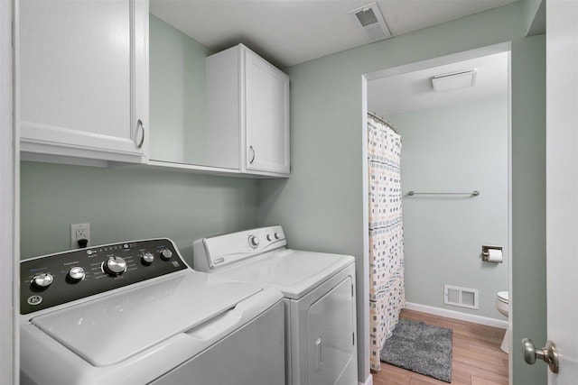 washroom with cabinets, light hardwood / wood-style floors, and washer and clothes dryer