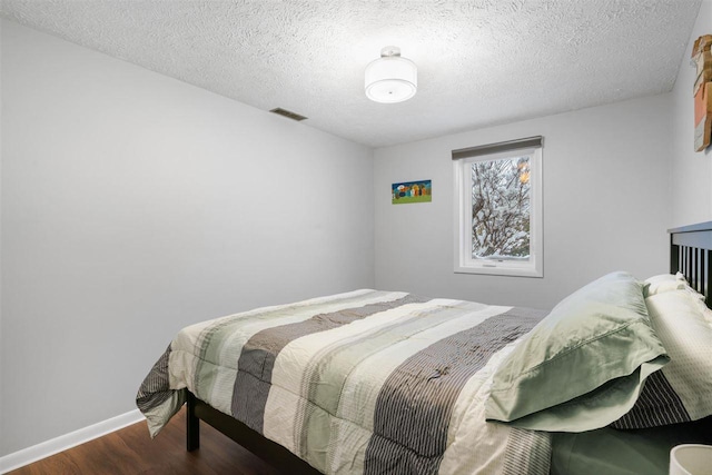 bedroom with a textured ceiling and dark hardwood / wood-style flooring