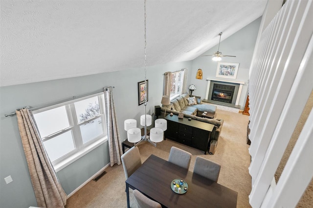 carpeted dining space featuring a textured ceiling, ceiling fan, and lofted ceiling