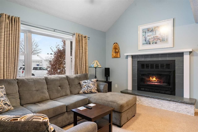 carpeted living room with a tiled fireplace and vaulted ceiling