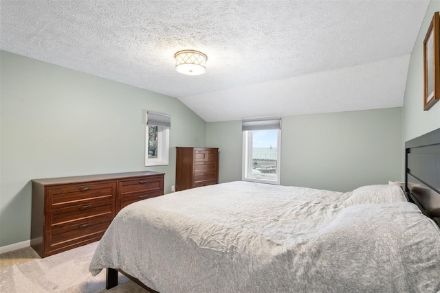 bedroom featuring lofted ceiling, a textured ceiling, and light carpet