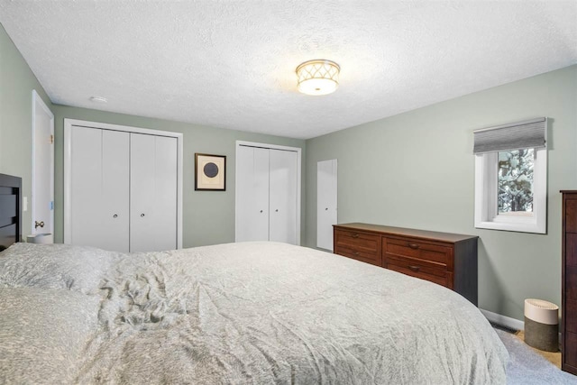 carpeted bedroom with a textured ceiling and multiple closets