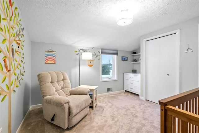 bedroom with a textured ceiling, vaulted ceiling, light carpet, and a nursery area