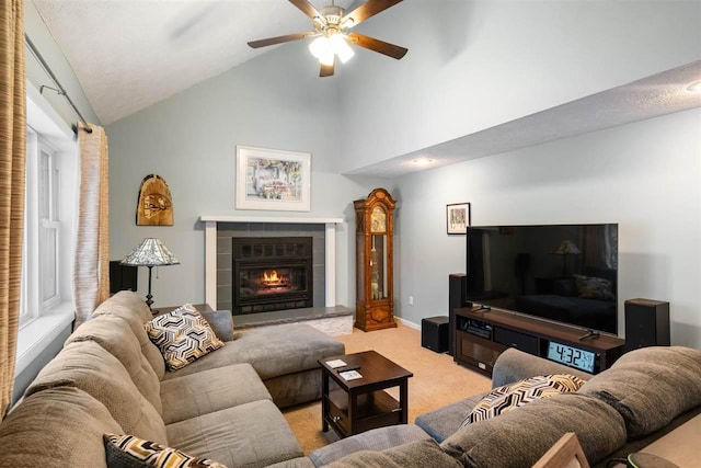 carpeted living room with ceiling fan, high vaulted ceiling, and a fireplace