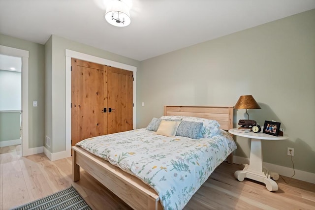 bedroom with light hardwood / wood-style floors and a closet