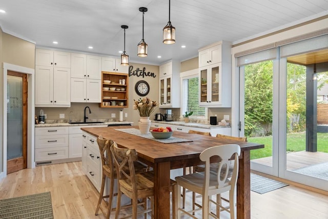 kitchen with sink, wooden ceiling, decorative light fixtures, white cabinetry, and light hardwood / wood-style floors