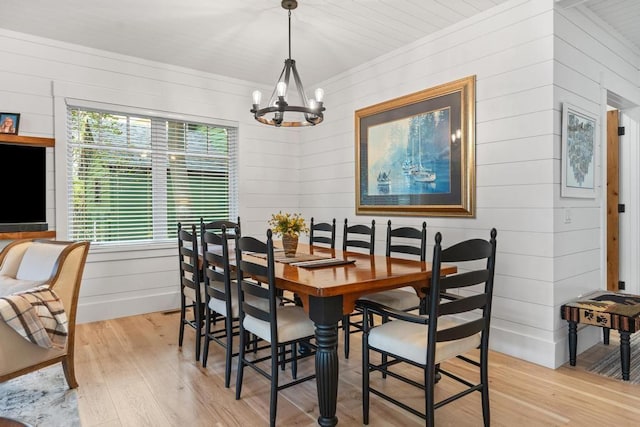 dining area with light wood-type flooring and a notable chandelier