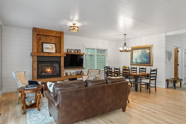 living room with a fireplace, an inviting chandelier, and light hardwood / wood-style floors