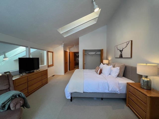 carpeted bedroom with a textured ceiling and vaulted ceiling with skylight