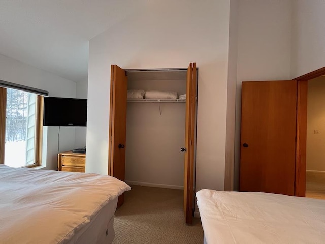 carpeted bedroom with a closet and vaulted ceiling