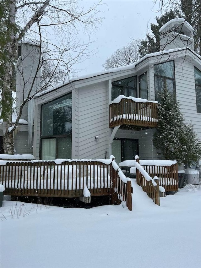 snow covered property featuring a balcony and a deck