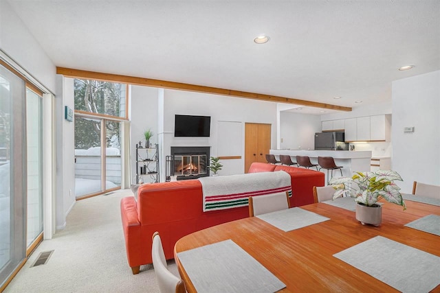 carpeted dining space featuring beamed ceiling