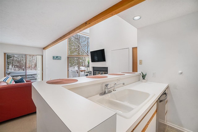 kitchen with sink, stainless steel dishwasher, lofted ceiling with beams, and kitchen peninsula