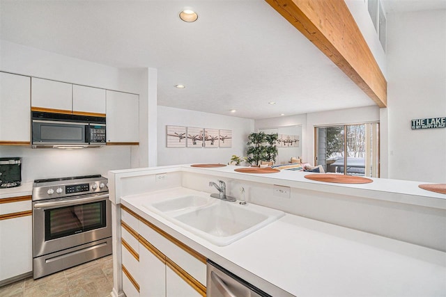 kitchen with electric range, white cabinetry, and sink